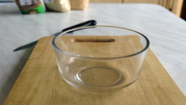 La pasta cruda se vierte en un recipiente transparente profundo para prepararla más tarde o clasificarla en una tabla de cortar de madera. cocina. cocina casera — Vídeo de stock