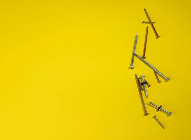 Çelik vidalar renkli arka planda. Sarı arka planda vidalar. Yazı için yer var. Site ve satış için alan.