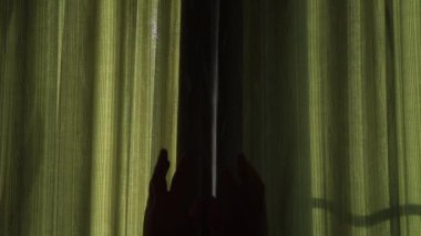 Karanlık bir odada perdeleri açar ve güneşin parlak ışığı belirir.