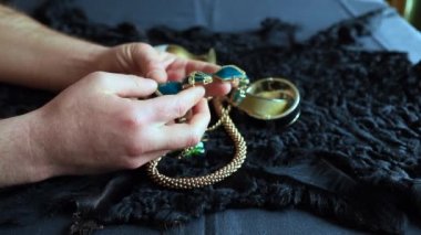 Bir adam masaya oturur ve mücevher ve mücevherleri toplar.
