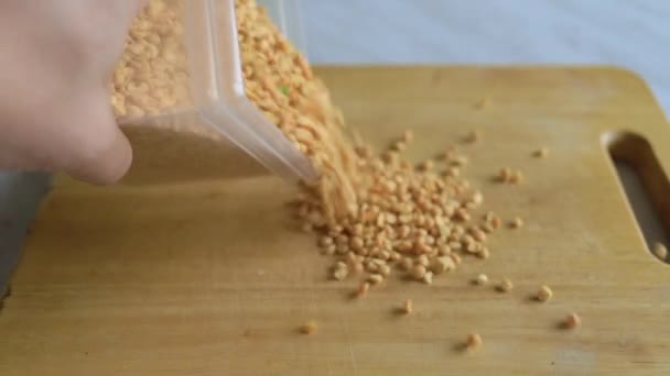 Erwten, uitgegoten uit een doorzichtige pot op een houten bord in de keuken — Stockvideo