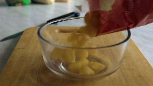 Rauwe pasta gegoten uit de zak in een transparante plaat — Stockvideo