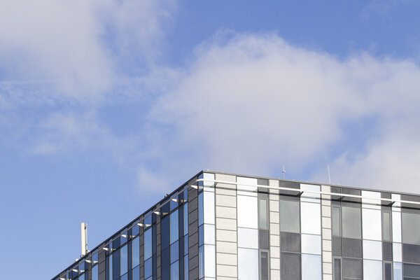 Modern office building made from glass and steel. Low angle view. Blue sky background. Copy space for text.