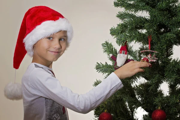 Retrato de niño feliz en Santa gorra decorando árbol de Navidad —  Fotos de Stock