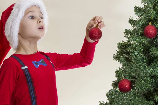 Niño en Santa gorra decorando árbol de Navidad —  Fotos de Stock