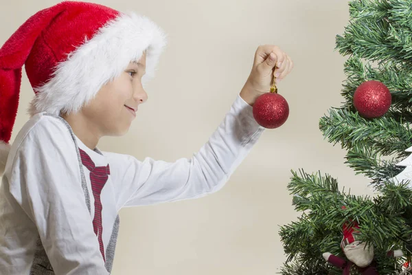 Niño feliz en Santa gorra decorando el árbol de Navidad —  Fotos de Stock