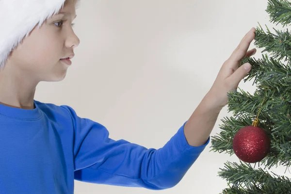 Boy in Santa cap near Christmas tree — Stock Photo, Image