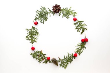Yeşil Mazı twigs, çam kozalakları ve beyaz zemin üzerine kırmızı yabani gül meyveler Noel çerçeve yaptı. Üstten Görünüm, düz yatıyordu. Metin için yer kopyalayın