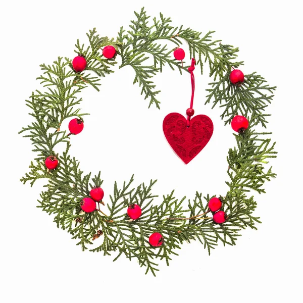 Χριστούγεννα Κάσια από πράσινο thuja κλαδιά, κόκκινο Άγριο Τριαντάφυλλο φρούτα και διακόσμηση δέντρο Χριστούγεννα αισθητές καρδιά σε άσπρο φόντο. Κάτοψη, επίπεδη lay. Χώρο αντίγραφο για το κείμενο — Φωτογραφία Αρχείου