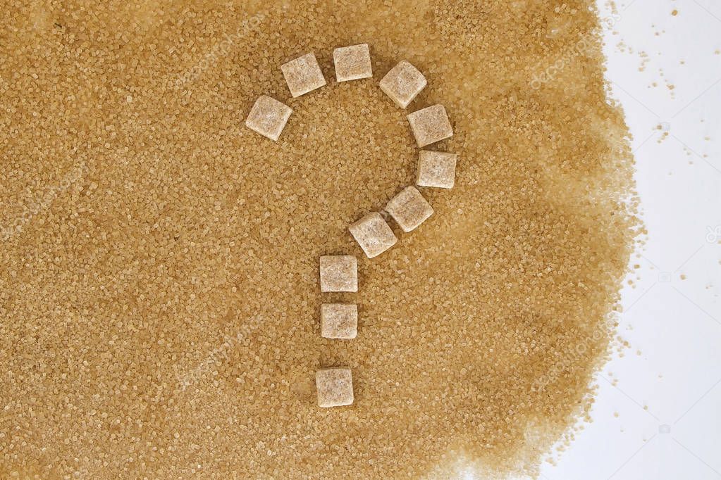 Background of brown sugar cubes shaped as a question mark. Top view. Diet unhealty sweet addiction concept