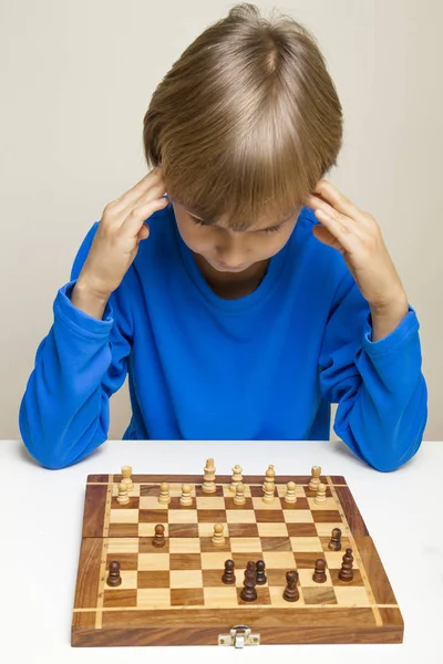 Маленька дитина дивиться на шахову дошку і думає про наступний хід . — стокове фото