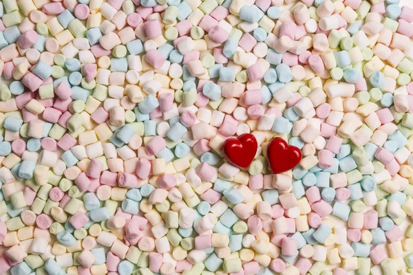 Two red hearts on colorful mini marshmallows background — Stock Photo, Image