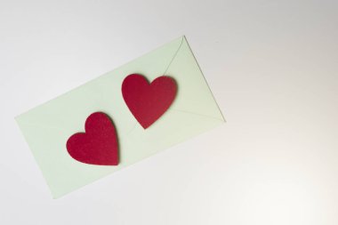 Yeşil zarf ve iki beyaz masada kırmızı kalpler hissettim. Üstten Görünüm.