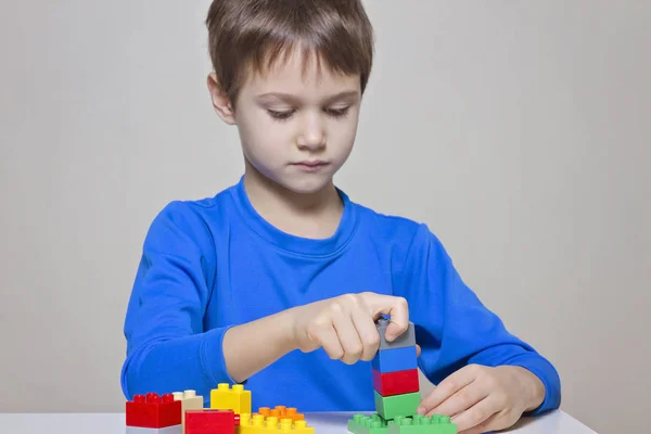 カラフルなプラスチック製の建設おもちゃブロック テーブルで遊んで子供男の子 — ストック写真