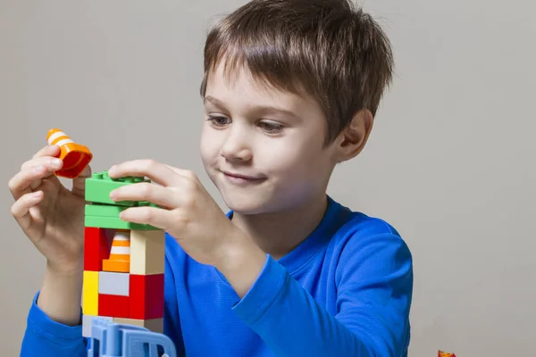Criança feliz brincando com blocos de brinquedo de construção de plástico colorido na mesa — Fotografia de Stock