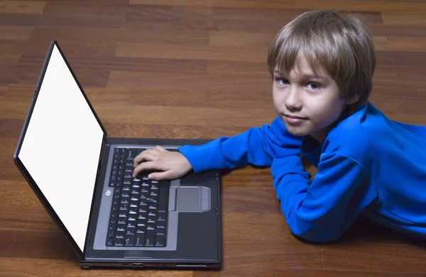 Child using laptop PC lying on wooden floor. Top view. Education, learning, technology concept — Stock Photo, Image