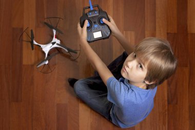 Küçük çocuk evde quadcopter drone ile oynayacak. Katta oturan ve bir radyo kontrol tutan çocuk