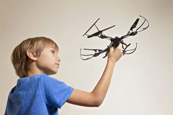 Colegial jugando con un dron. Niño sosteniendo quadcopter en su mano, preparándose para volar — Foto de Stock