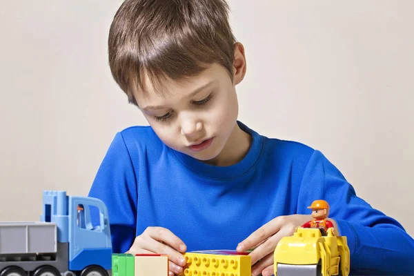 Criança concentrada brincando com brinquedos de construção de plástico colorido na mesa. Fechar — Fotografia de Stock