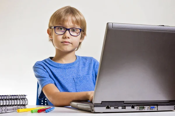 Menino com óculos usando computador portátil enquanto sentado na mesa em casa. Tecnologia, conceito de educação — Fotografia de Stock