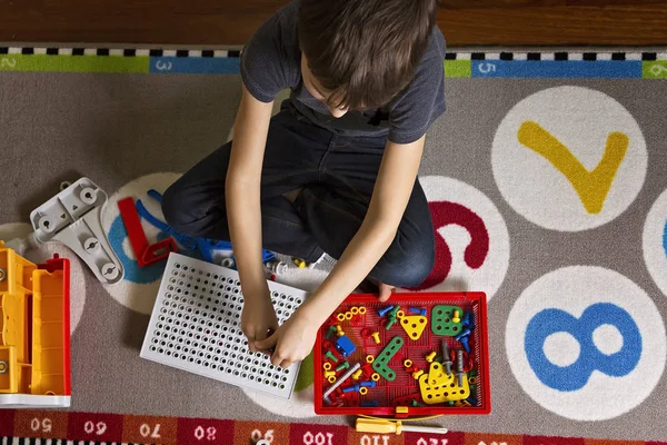 Criança brincando com brinquedos kit de ferramentas enquanto sentado no chão em seu quarto.Vista superior — Fotografia de Stock