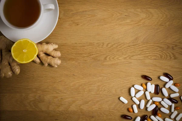 Elija entre la medicina tradicional y popular. Taza de té, limón, jengibre, diferentes píldoras sobre fondo de madera. Vista superior. Copiar espacio. Concepto de salud . —  Fotos de Stock