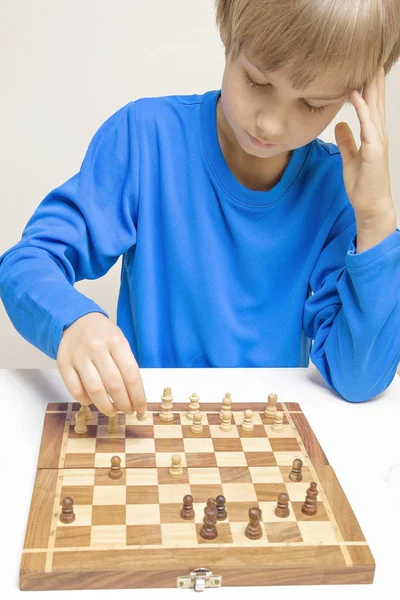Портрет маленького кавказького хлопчика, який грає в шахи і робить наступний крок — стокове фото
