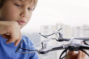 Drone ile oynayan çocuk. Çocuğun pencerenin quadrocopter elinde tutan yakınındaki. Teknoloji, eğlence oyuncaklar kavramı