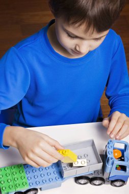 Renkli plastik inşaat tuğla ve oyuncak araba ile evde oynarken mutlu çocuk