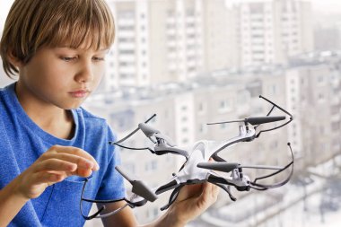 Drone ile oynayan çocuk. Çocuğun pencerenin quadrocopter elinde tutan yakınındaki. Teknoloji, eğlence oyuncaklar kavramı