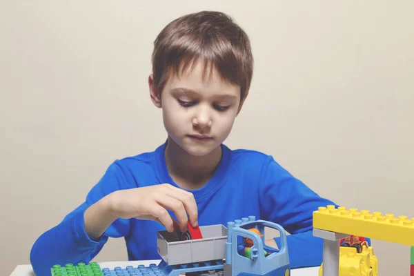 Menino brincando com blocos de brinquedo de construção de plástico colorido na mesa — Fotografia de Stock