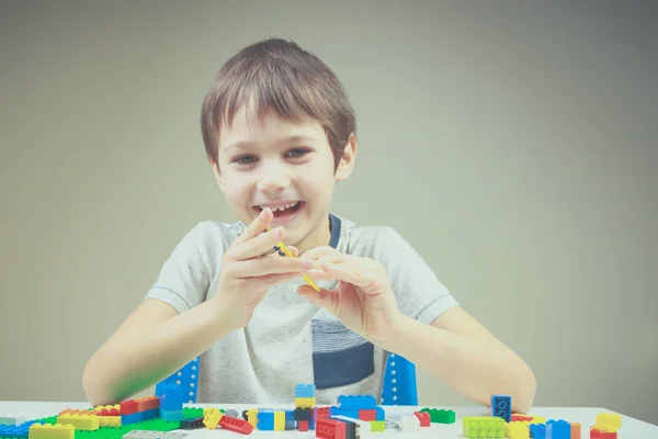 Sorrindo criança brincando com tijolos de construção de plástico colorido em casa — Fotografia de Stock