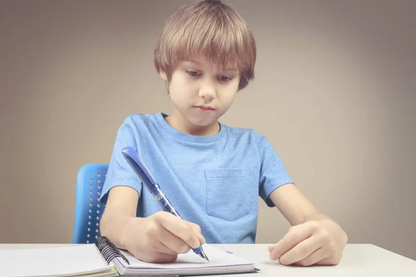 Garçon en utilisant un stylo et en écrivant sur un cahier en spirale. Garçon faire ses exercices de devoirs — Photo