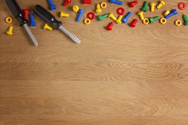 Çocuklar inşaat oyuncak araçları: renkli Tornavidalar, vida ve somunlar ahşap arka plan üzerinde. Üstten Görünüm. Düz yatıyordu. Metin için yer kopyalayın