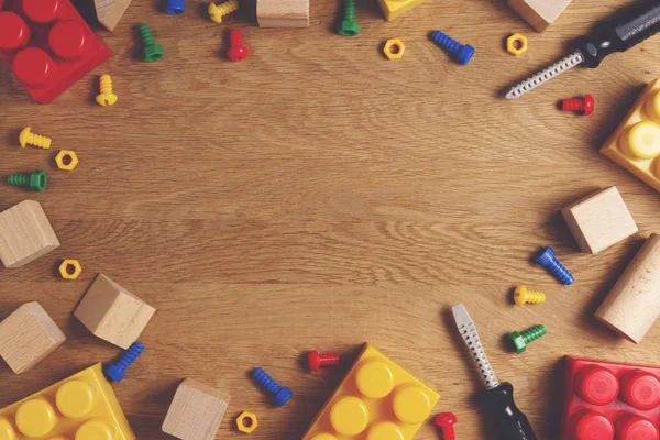 Los juguetes para niños enmarcan el fondo con herramientas de juguete, bloques y cubos en una mesa de madera. Vista superior. Acostado. Copiar espacio para texto — Foto de Stock