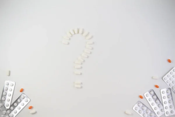 Comprimidos em forma de ponto de interrogação e comprimidos sobre fundo branco. Médico, conceito de saúde . — Fotografia de Stock