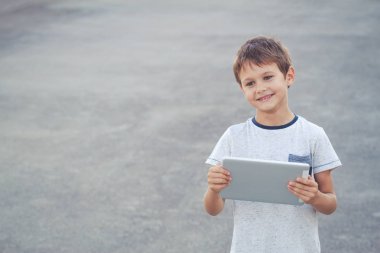Gülümseyen çocuk tutun tablet bilgisayar. Okul, eğitim, teknoloji, eğlence kavramı