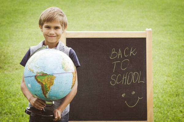 Schoolboy with a globe against the blackboard. Education Back to school concept