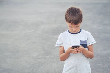 Cep telefonu olan çocuk. Okul, insanlar, teknoloji, eğlence kavramı