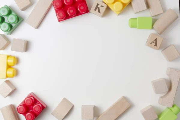 Blocs de construction en plastique coloré et cubes en bois sur fond blanc comme cadre de jouets pour enfants. Pose plate. Vue du dessus — Photo