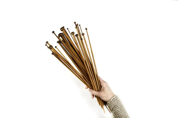 Mulher mão segurando um monte de agulhas de tricô de madeira no fundo branco — Fotografia de Stock