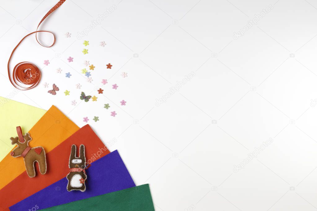 Colorful felt, sewing accessories and handmade toys on white background.