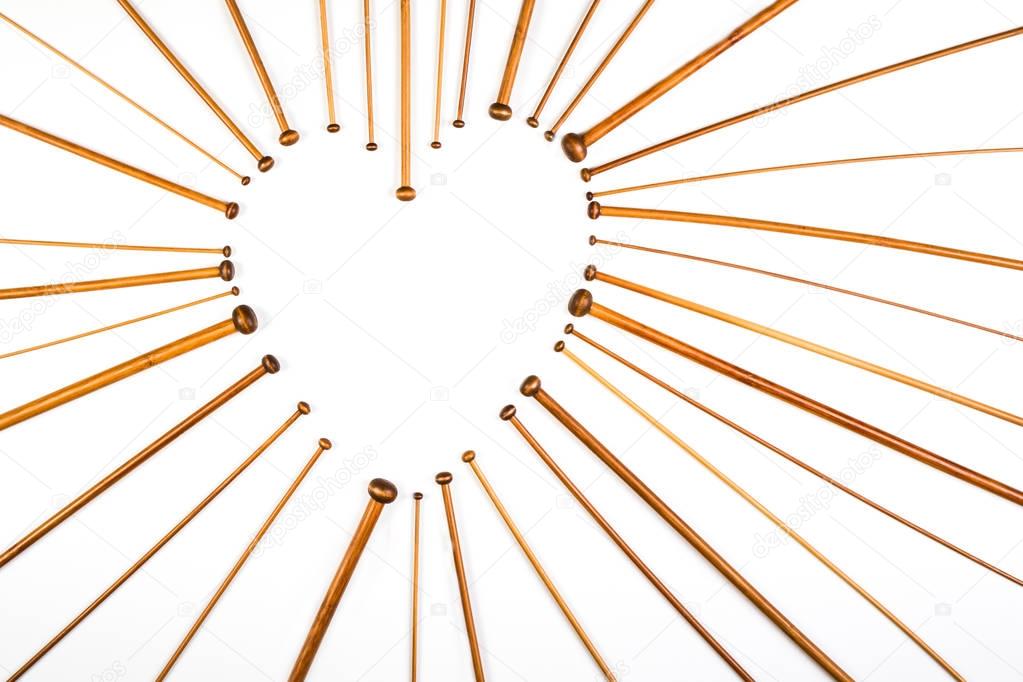 Heart symbol made of wooden knitting needles on white background.