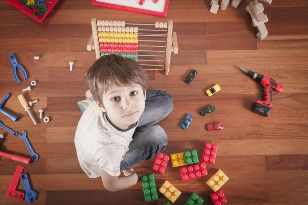 Criança brincando com brinquedos enquanto se senta no chão de madeira em seu quarto.Vista superior — Fotografia de Stock