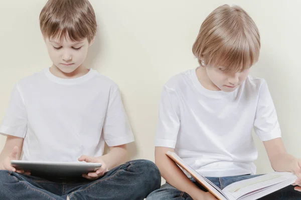 Rapaz com tablet e miúdo a ler um livro. Crianças educação conceito de lazer . — Fotografia de Stock