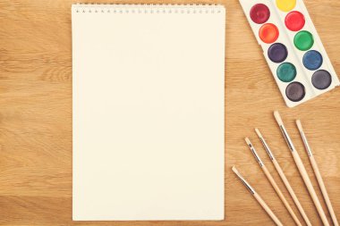 Suluboya boya, fırça ve ahşap arka plan sayfasındaki boş beyaz kağıt.