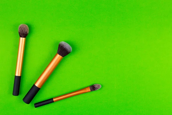 Maquillaje cepillos sobre fondo verde — Foto de Stock