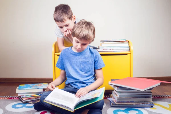 Děti čtení knihy. Chlapec se čte příběh svého bratra doma — Stock fotografie