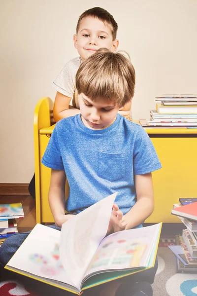 Děti čtení knihy. Chlapec se čte příběh svého bratra doma — Stock fotografie