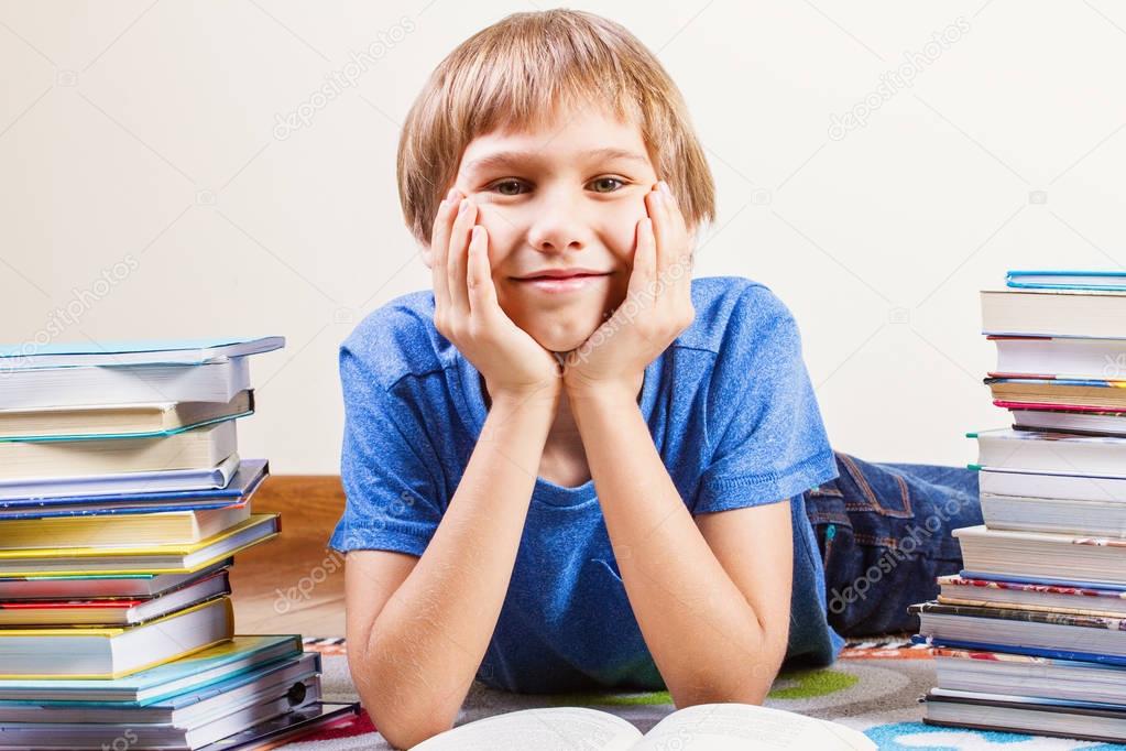 Smiling boy between the stacks of books.